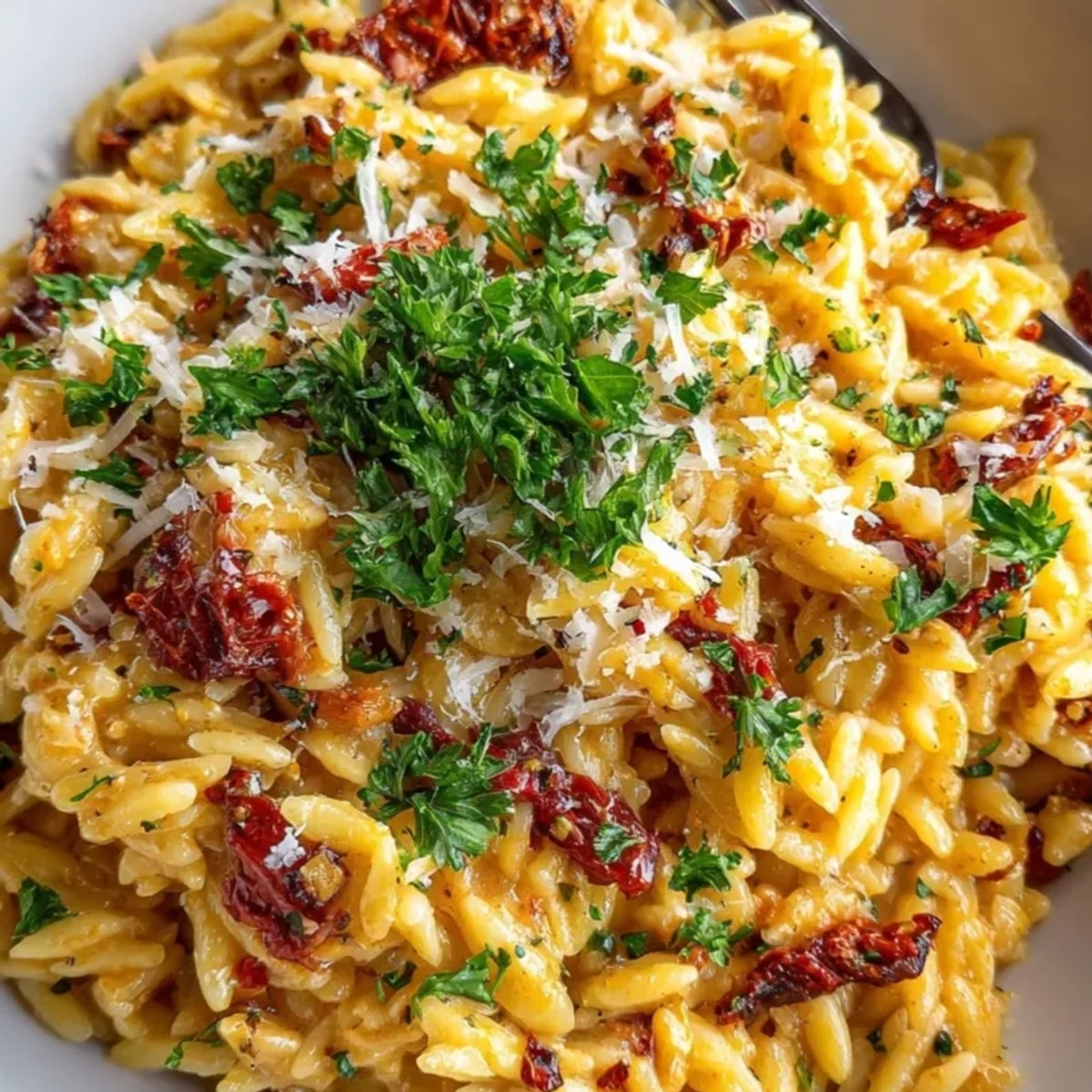 Scoops of sun-dried tomato pesto orzo, a bright and herby Italian pasta salad.