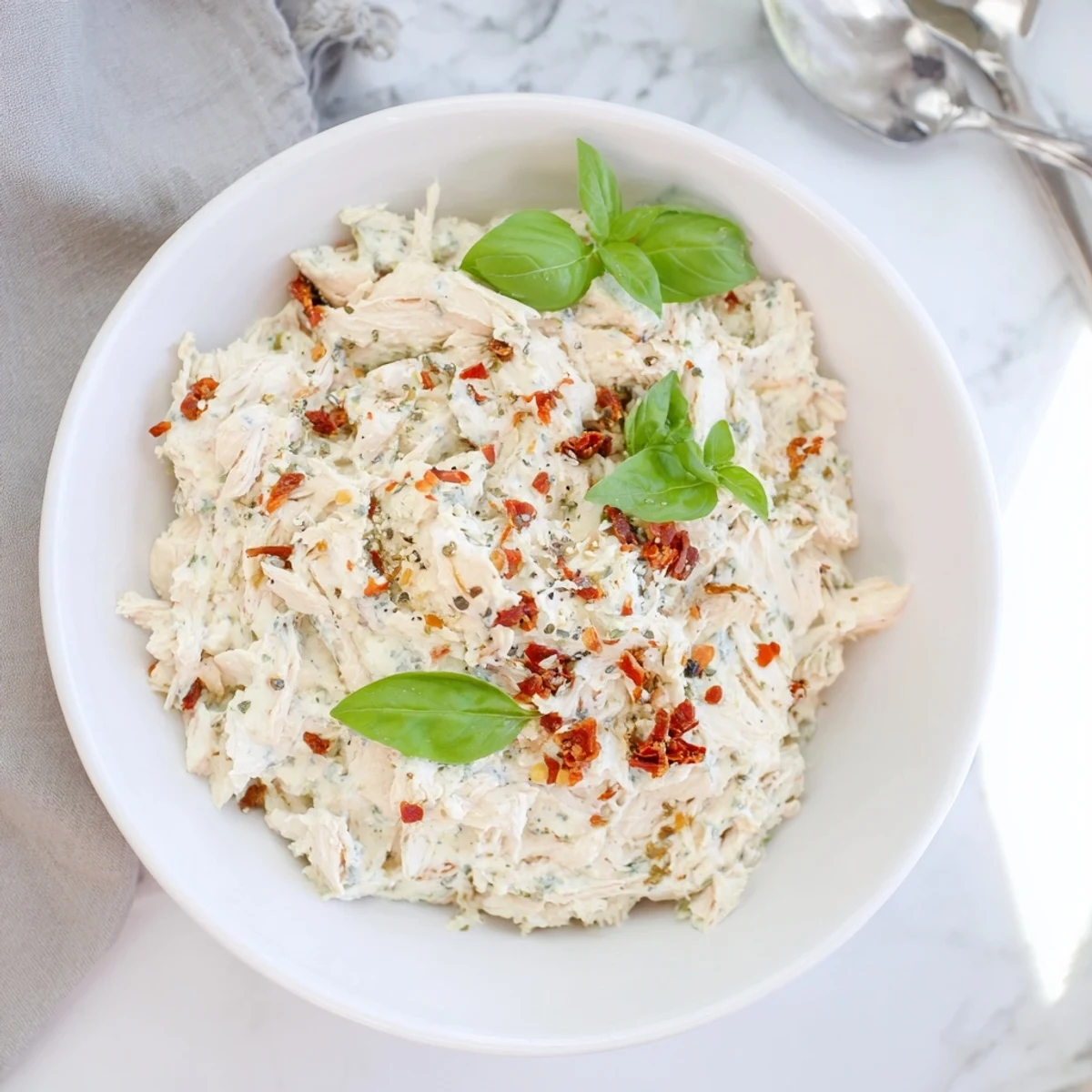 Creamy, bubbling Lightened Marry Me Chicken Dip, golden brown on top, perfect with fresh basil garnish.