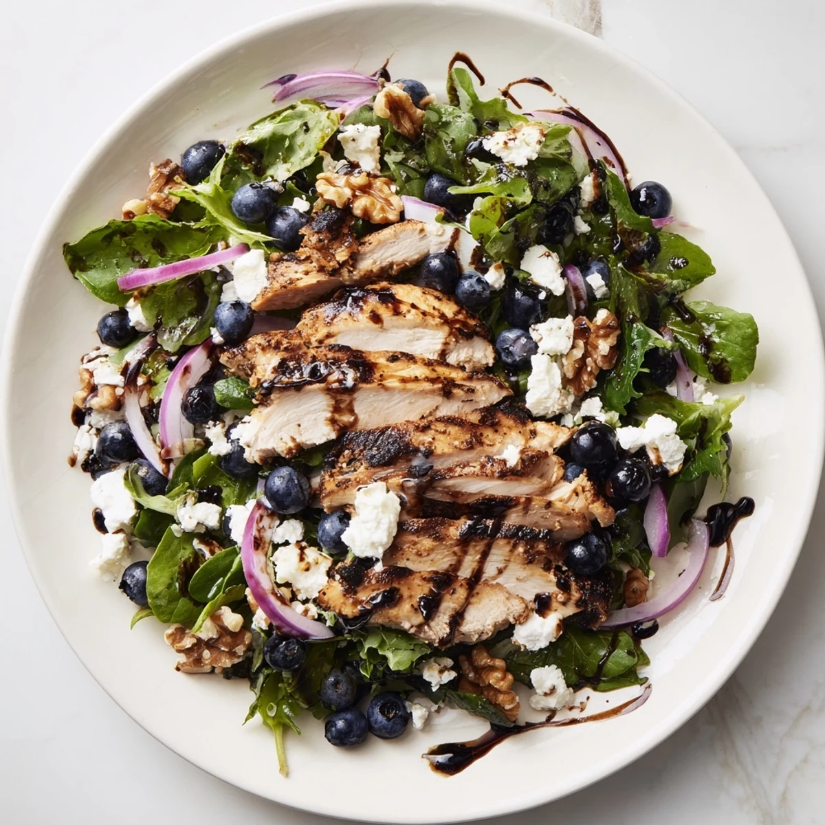Tender slices of chicken atop a vibrant Blueberry Goat Cheese Chicken Salad, ready to enjoy.