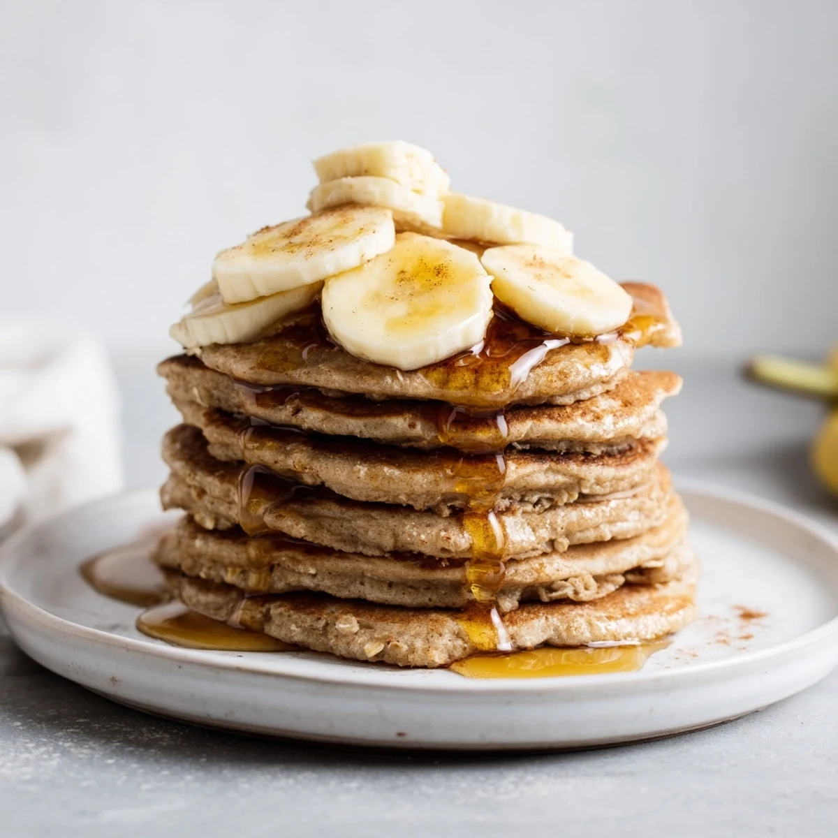 Golden-brown banana oat pancakes stacked high, ready to be drizzled with maple syrup.
