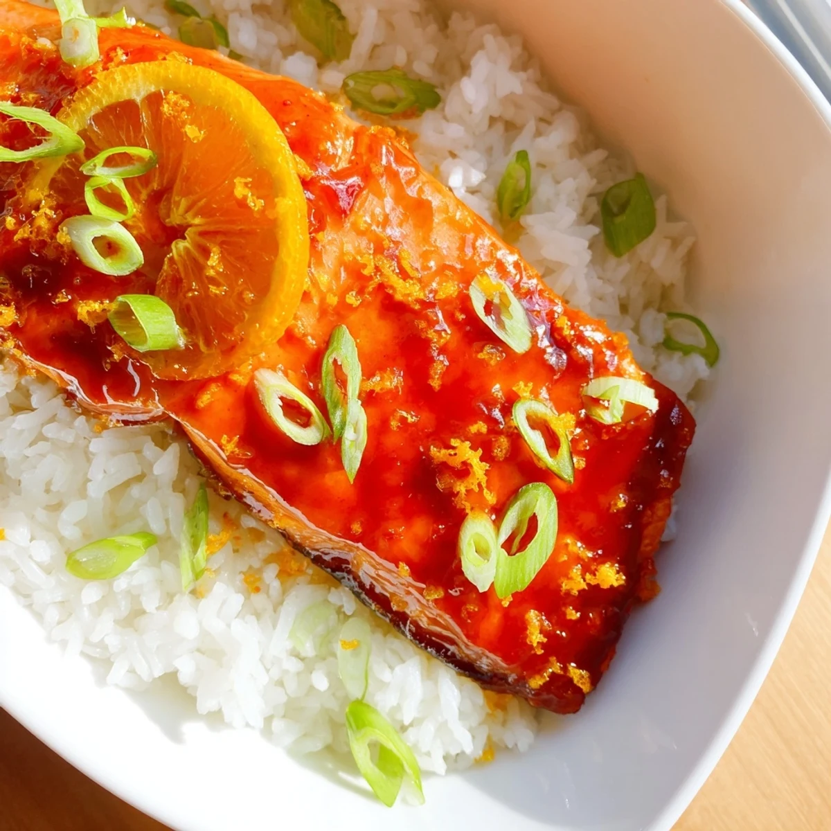 A close-up of vibrant Sticky Orange Salmon, glistening with sauce and served with fluffy rice.