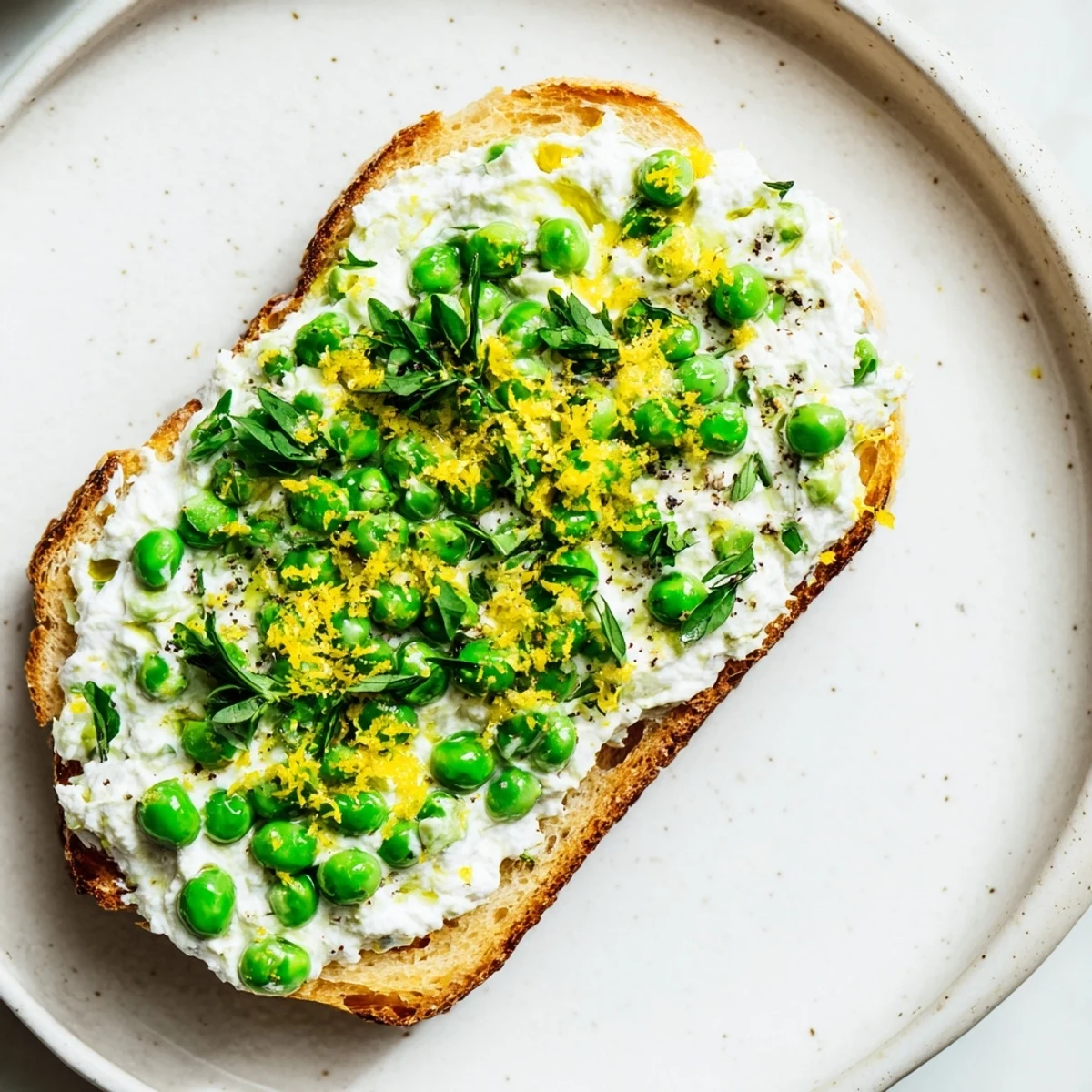 Creamy pea & mint ricotta toast with fresh mint and lemon zest, a vibrant vegetarian treat.