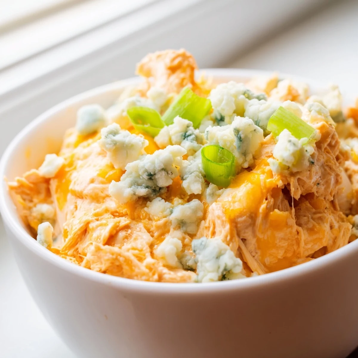 Golden, bubbly Buffalo Chicken Dip fresh from the oven, served with crisp celery sticks and carrots for a classic game-day snack.  