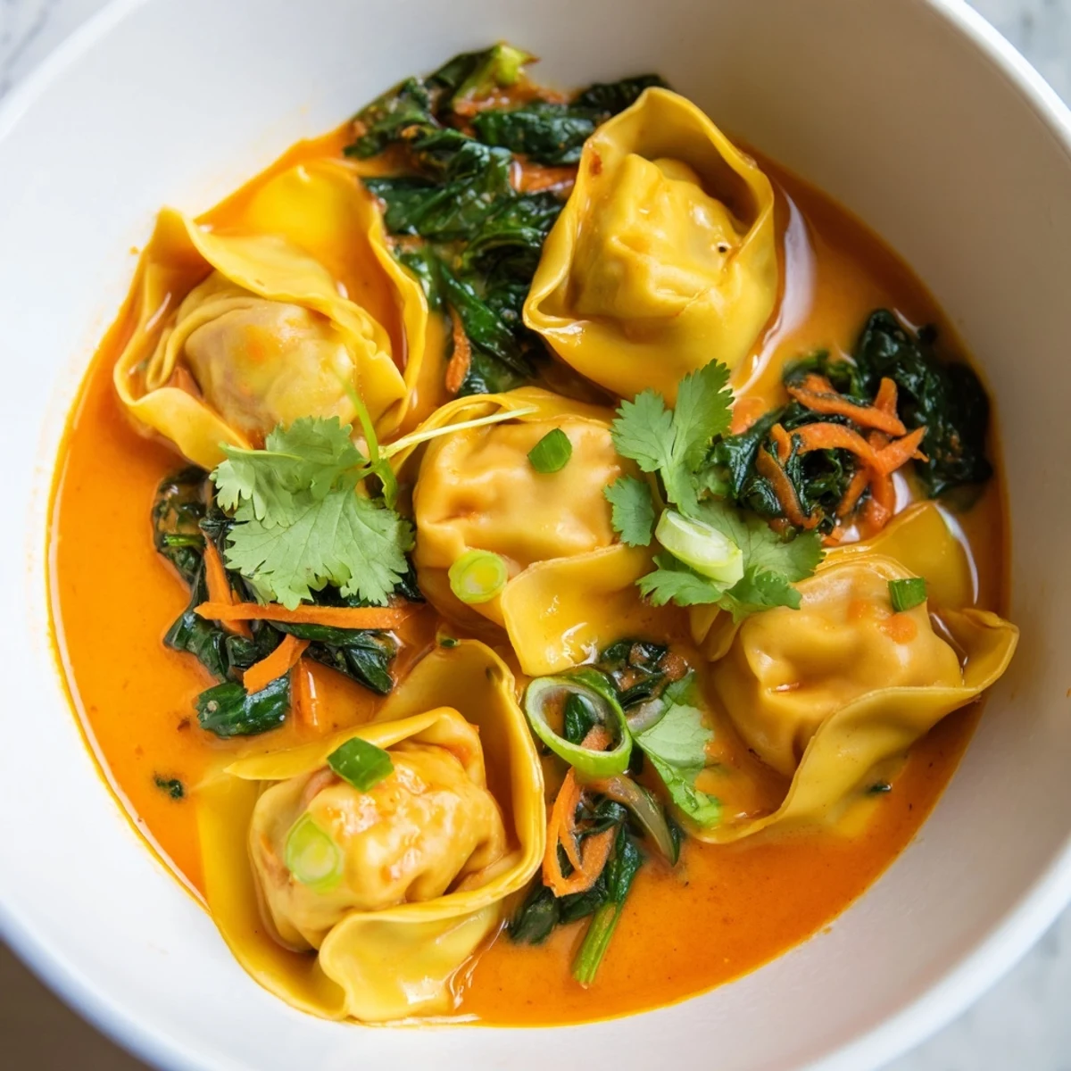 Fragrant Red Curry Wonton Soup With Greens topped with cilantro and chili, paired with jasmine rice.