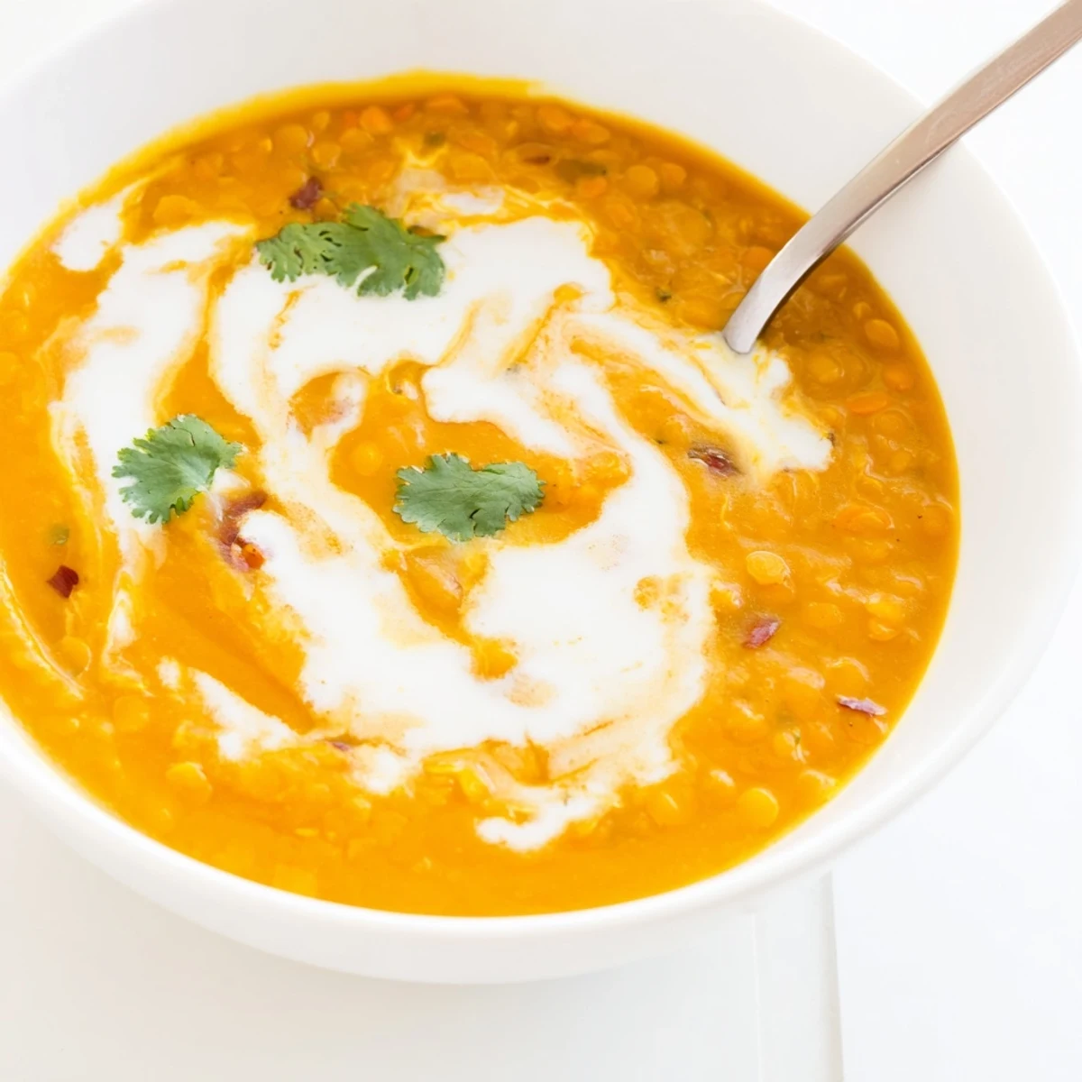 Steaming ladle of velvety Butternut Squash and Lentil Soup, highlighting the rich orange color and warming spices.