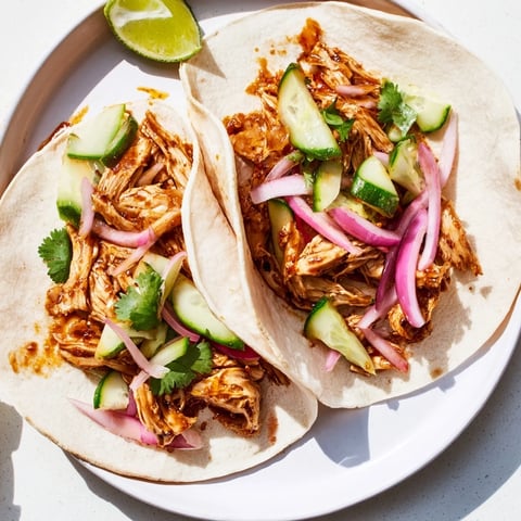 Tender, flavorful sticky chicken tikka masala tacos served with fresh cilantro and cool lime wedges.