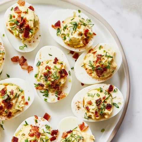 Creamy Loaded Deviled Eggs: A close-up shows bacon crumbles and smoked paprika adding savory flavor.