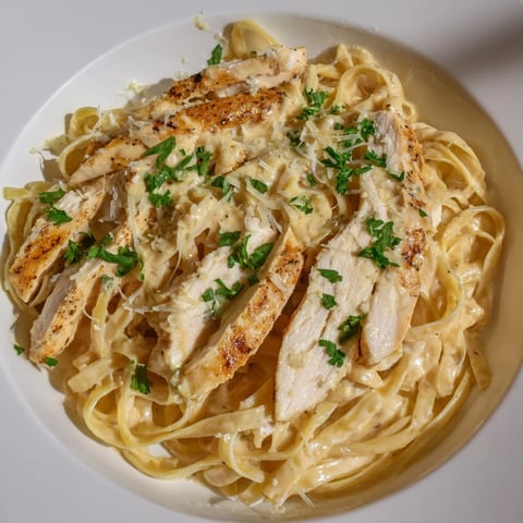 Tender sliced Cajun chicken tops creamy Cajun Chicken Alfredo Fettuccine Pasta with vibrant parsley garnish.