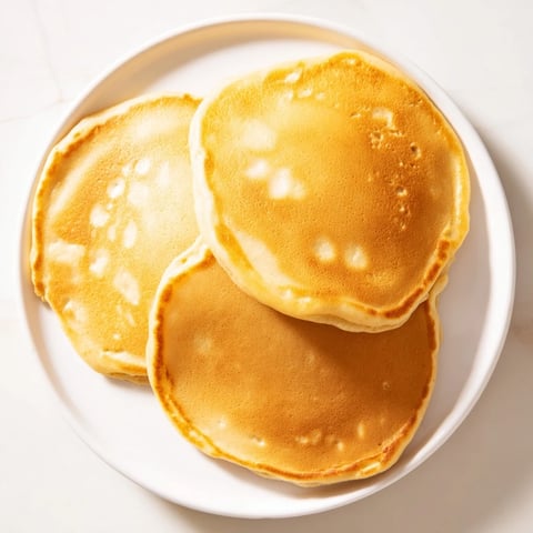 Fluffy brown banana pancakes, golden and cooked, ready to be enjoyed with fresh fruit.
