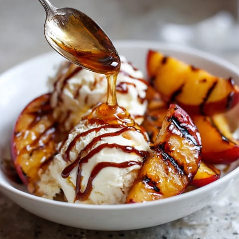 A bowl of grilled peaches with honey and vanilla ice cream.