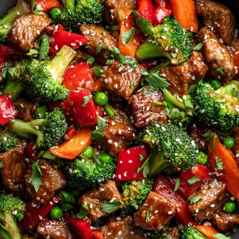 A stir fry with beef, broccoli, carrots, peppers, and peas.