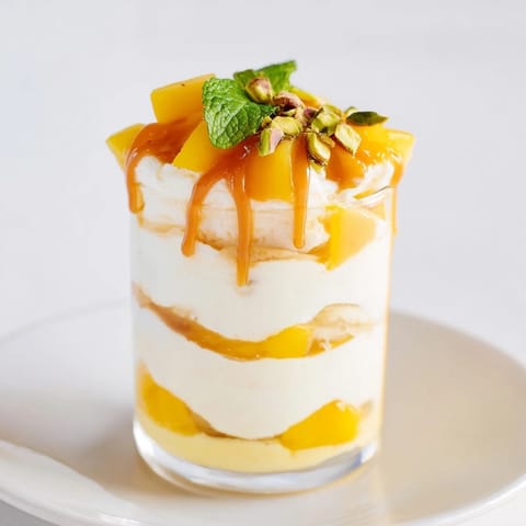 Decadent mango caramel ricotta parfait, garnished with pistachios and fresh mint leaves.  