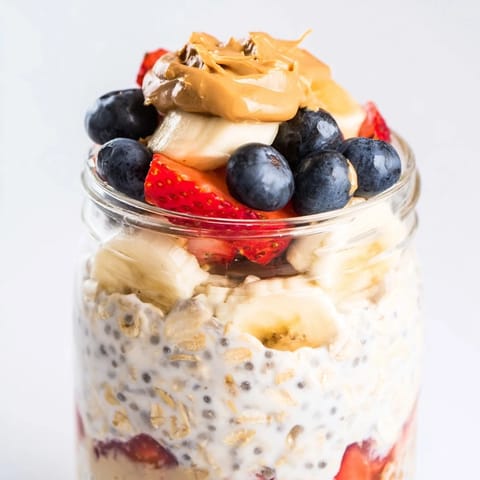 Close-up of overnight oats jars, showing vibrant layers of fruit, creamy oats, and peanut butter swirls.
