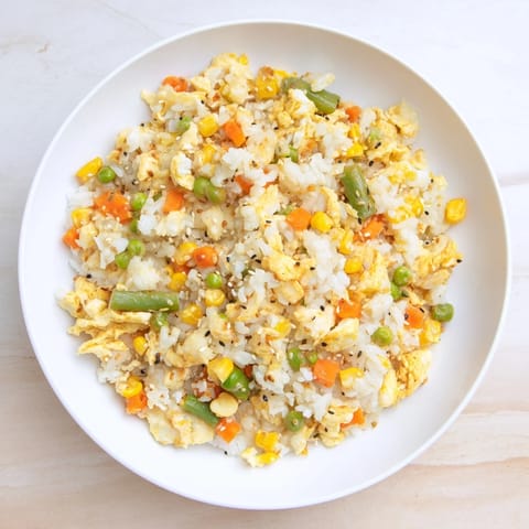 Steaming plate of Frozen Veggie Fried Rice, mixed with vegetables and savory soy sauce.