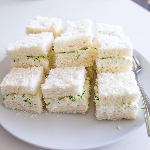 Creamy filling bursting from these Snowball Tea Sandwich Bites, perfectly coated in sweet coconut flakes.