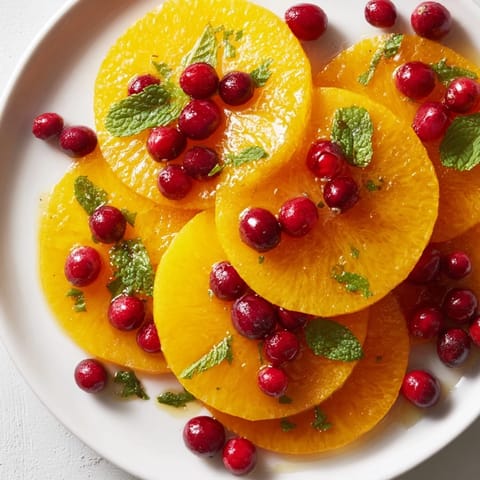 Brightly colored orange slices and cranberries, ready to be tossed in a simple honey lime dressing