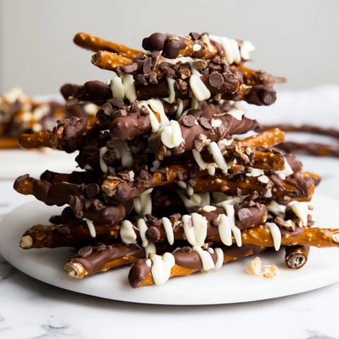 Sweet white chocolate drizzles highlight the decadent, homemade Chocolate Covered Pretzel Stick Stacks, ready to eat!