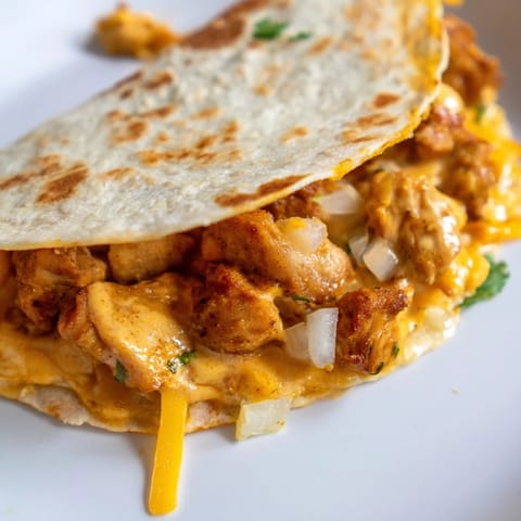 A close-up shows the melted cheese and spiced chicken inside a crispy Butter Chicken Quesadilla.