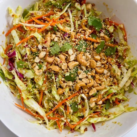 Vibrant Asian Cabbage Salad served in a rustic bowl, featuring julienned carrots and sliced green onions for a colorful, refreshing side dish.  