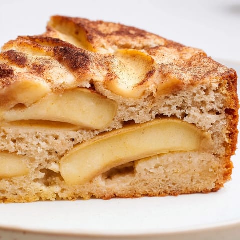 Golden baked apple cake fresh from the oven, featuring soft apple slices and a spiced, cobbler-like topping.