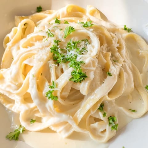 Velvety Easy Creamy Cauliflower Alfredo sauce coats fettuccine in a white bowl, with warm bread alongside for dipping.