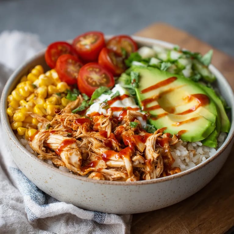 A bowl of food with chicken, tomatoes, avocado, and rice.