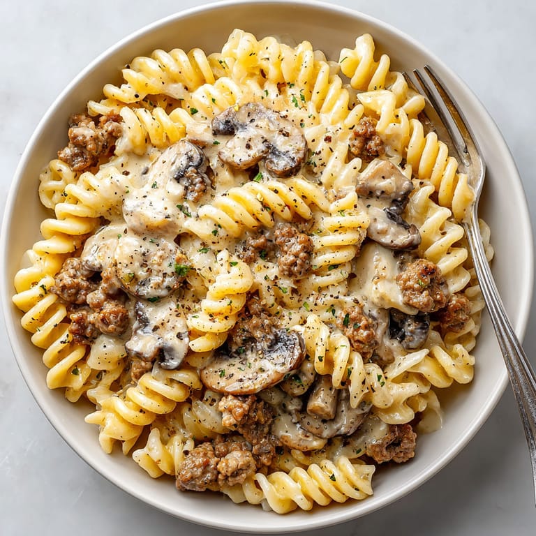 A bowl of pasta with mushrooms and meat.