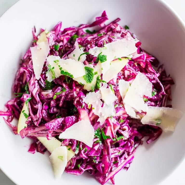 Bright and crunchy Red Cabbage Coleslaw with Apple and Parmesan served on a wooden table, garnished with fresh herbs for a fresh side dish.