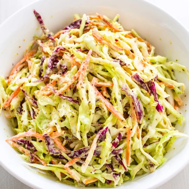 Freshly mixed Coleslaw With Creamy Dressing featuring crunchy cabbage, carrots, and a smooth, savory dressing in a serving bowl.