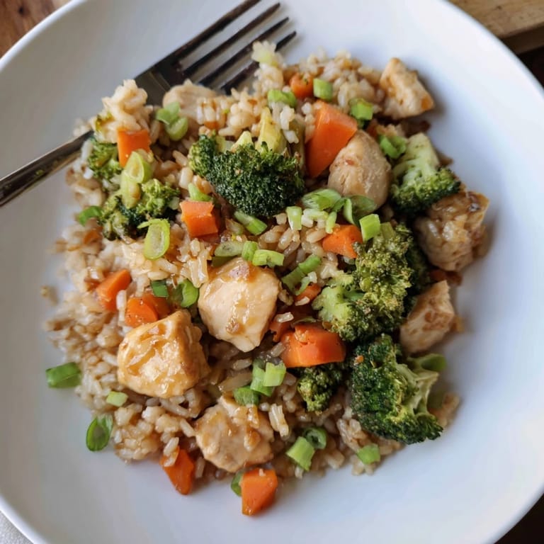 A close-up of One Pan Honey Garlic Chicken Broccoli Rice showing fluffy rice grains, diced carrots, and juicy chicken tossed in a sweet, garlicky glaze.