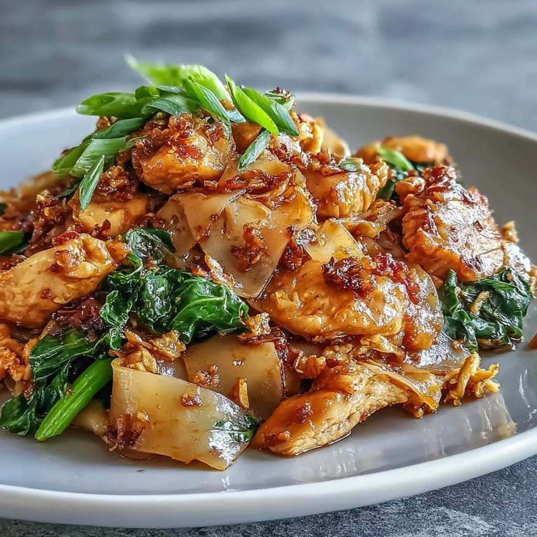 Freshly stir-fried Authentic Thai Pad See Ew tossed with wide noodles and savory-sweet sauce in a wok.